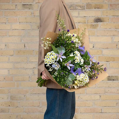 Smuk tak for dig blomsterbuket i lilla og hvide farver med asters, klematis og hindebæger