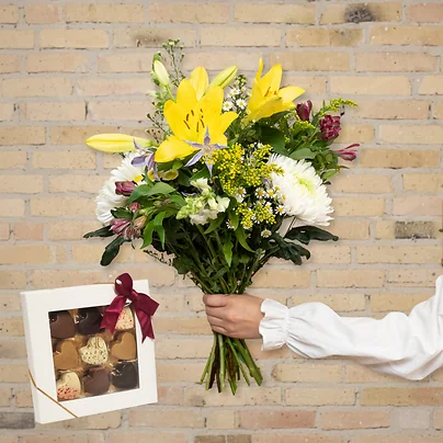 Send en smuk og trendy forårsbuket med chokoladehjerter og liljer